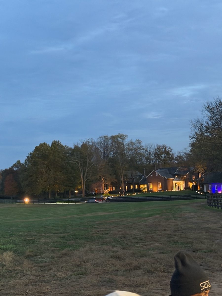 Kentucky horse farm at dusk with the house lit and black plank fencing across the pasture during a private event