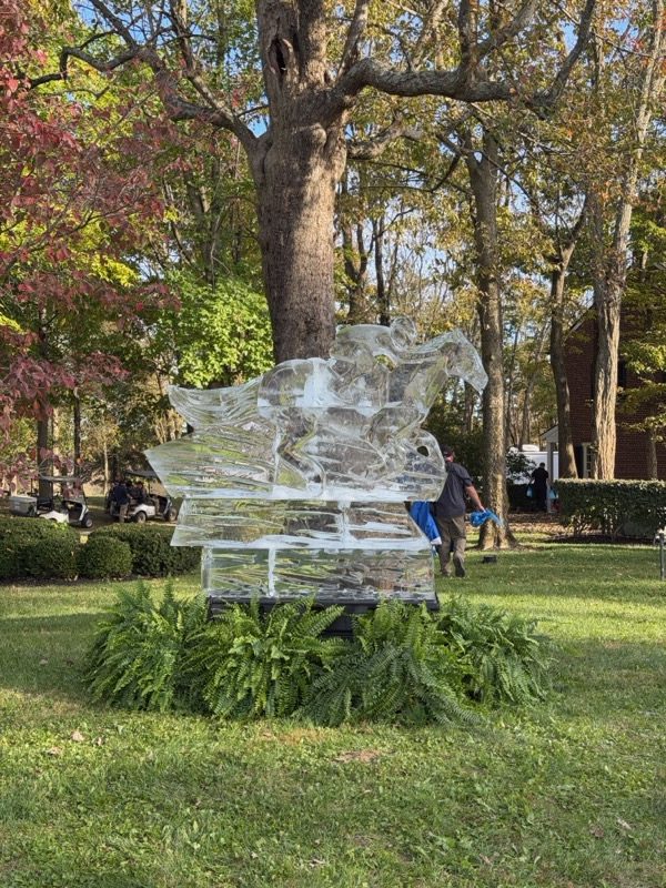 Horse and jockey ice sculpture on the lawn at a private Breeders' Cup week event in Paris, Kentucky, with guest shuttle carts in the background