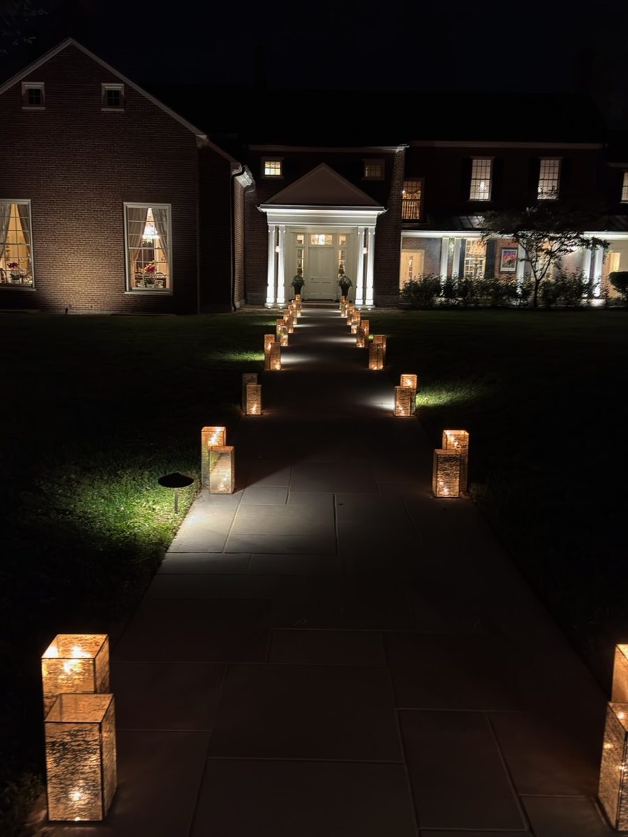 Lantern-lined stone walkway leading to a lit front entrance at a private Kentucky farm event at night